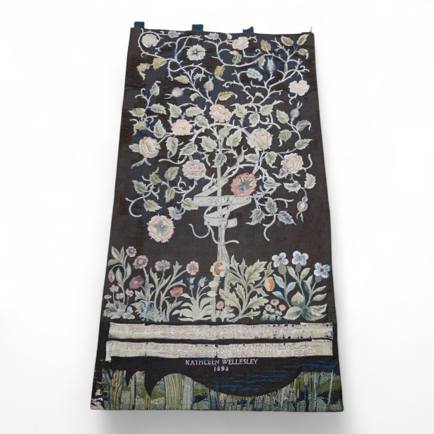 A large Arts and Crafts silk embroidered wall hanging, embroidered in the manner of May Morris with a large central scrolling flowering rose tree and banner embroidered with Salve and a two row motto below;, Rose leaves